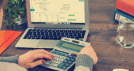 A calculator and laptop with documents that are needed for taxes after a house is sold.