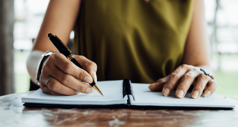 An image of a woman writing a due diligence real estate checklist.