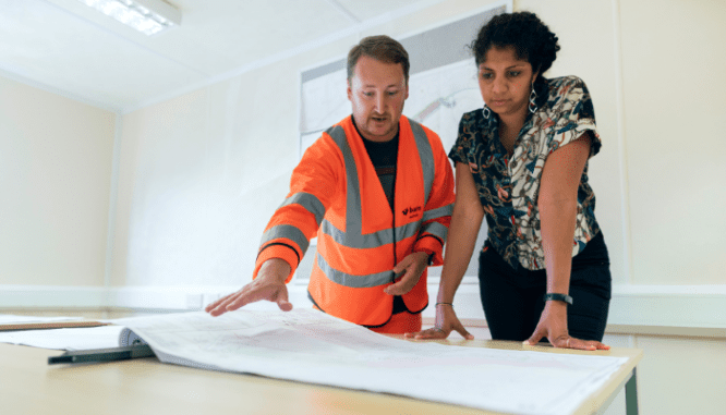 Two people looking at blueprints for their new construction home, for which they'll want a new home inspection checklist.